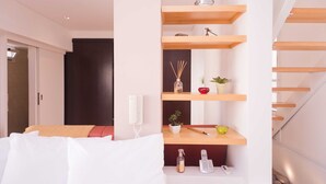 A modern hotel room with a bed, a wooden shelf unit with decorative items, a telephone, and a small plant. - Billinghurst 2 by Be Local Argentina (Buenos Aires)