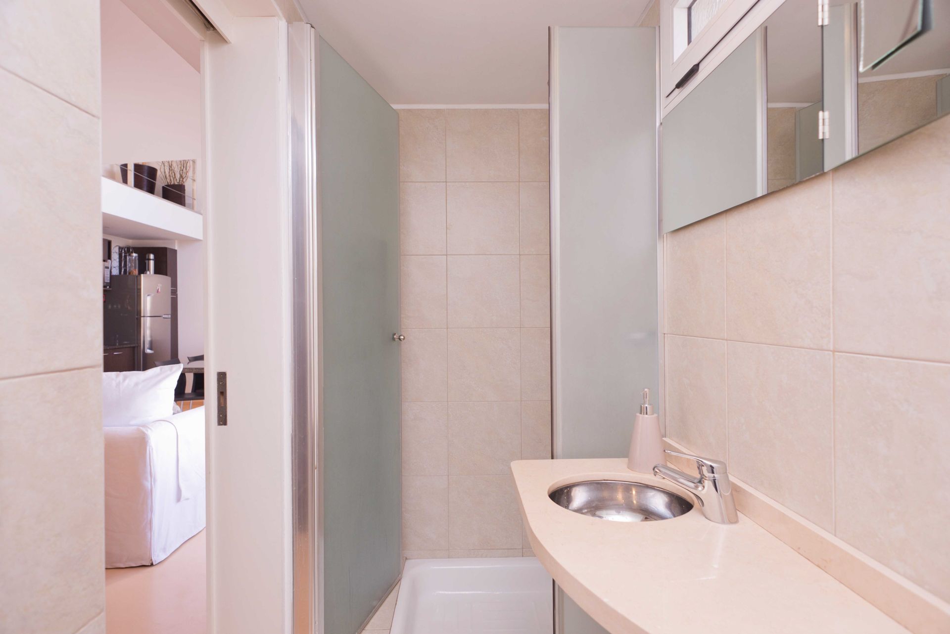 A modern bathroom with a sink, mirror, and a shower area.