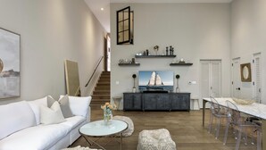 A modern living room with a white sofa, a round coffee table, and a dining area with a glass table and chairs. - Luxury Condo in Heart of Downtown Santa Barbara  (Santa Barbara)