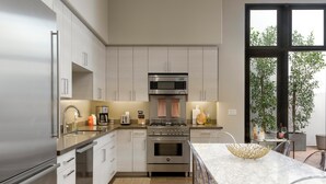 A modern kitchen with stainless steel appliances, a marble countertop, and a view of greenery outside. - Luxury Condo in Heart of Downtown Santa Barbara  (Santa Barbara)