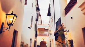 A narrow alleyway between buildings with white walls, a balcony, and a street lamp. - Luxury Condo in Heart of Downtown Santa Barbara  (Santa Barbara)