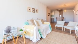 Een moderne woonkamer met een zithoek, een glazen salontafel en een bijzettafeltje.