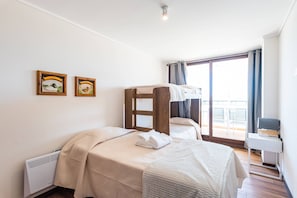 Una camera d'albergo con due letti, una scrivania e un balcone con vista.