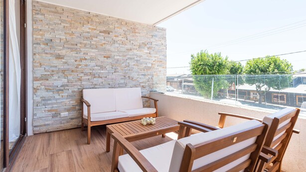 Een balkon met een stenen muur, een bank en houten meubels.