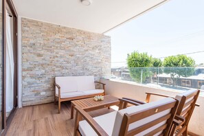Ein Balkon mit einer Steinmauer, einer Couch und Holzmöbeln.