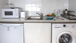 Eine kleine Küche mit Mikrowelle, Toaster, Wasserkocher, Spüle und Waschmaschine.