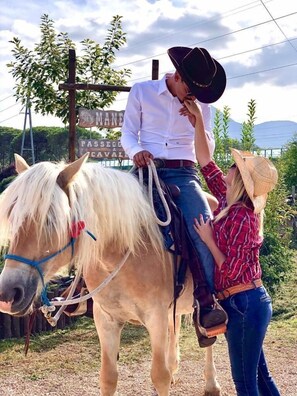 A person in a cowboy hat and white shirt riding a horse. - La Tenuta del Campo di Sopra (Patrica)