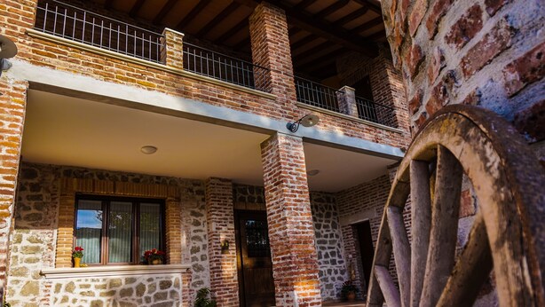 A stone building with a balcony, a wooden door, and potted plants.
