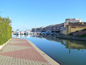Un port de plaisance avec des bateaux amarrés, une promenade pavée et des immeubles résidentiels en arrière-plan.