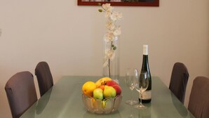 Ein Esstisch mit Obstschale, Weinflasche und Gläsern.