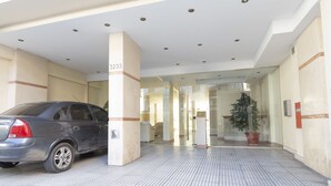 Auto oli pysäköitynä rakennuksen eteen, ja rakennuksessa oli laatoitettu lattia sekä lasinen sisäänkäynti.