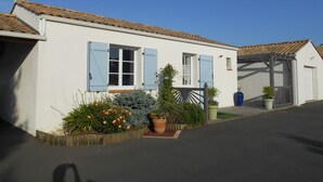 Un bâtiment blanc avec des volets bleus, un toit en tuiles et un porche abrité.