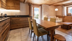 A wooden interior with a kitchen, dining area, and a sofa. - Cozy 4* apartment, south terrace, near slopes, parking, Wi-Fi (La Clusaz)