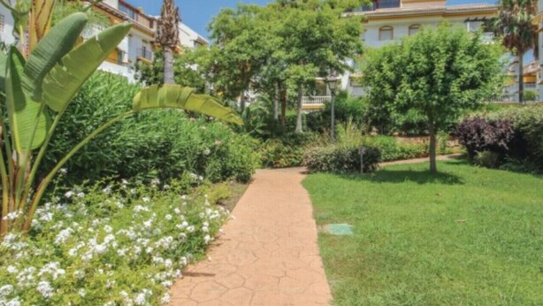 Ein Weg, der durch einen gepflegten Garten mit verschiedenen Pflanzen und Bäumen führt.