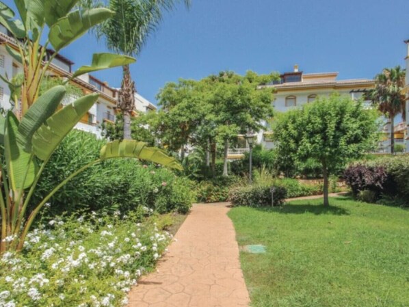 A pathway leading through a well-maintained garden with various plants and trees.