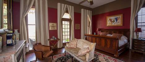 A room with a bed, a sofa, a chair, a fireplace, and a ceiling fan.