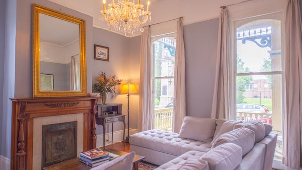 Sala de estar com lareira, um espelho grande, um candelabro, um sofá e vista para uma ponte.