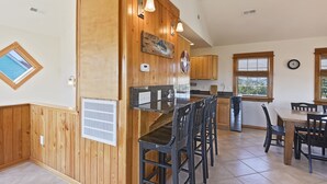 A kitchen with wooden paneling, a bar area, and a dining table with chairs. - Semi Ocean Front in Nags Head NC with Private Pool! (Nags Head)