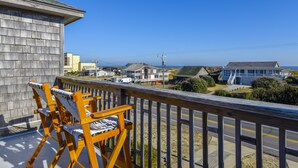A balcony with wooden chairs, a view of the road, and buildings in the distance. - Semi Ocean Front in Nags Head NC with Private Pool! (Nags Head)