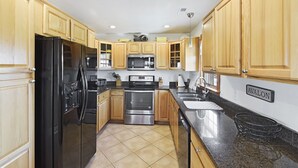 A kitchen with wooden cabinets, stainless steel appliances, and a granite countertop. - Semi Ocean Front in Nags Head NC with Private Pool! (Nags Head)