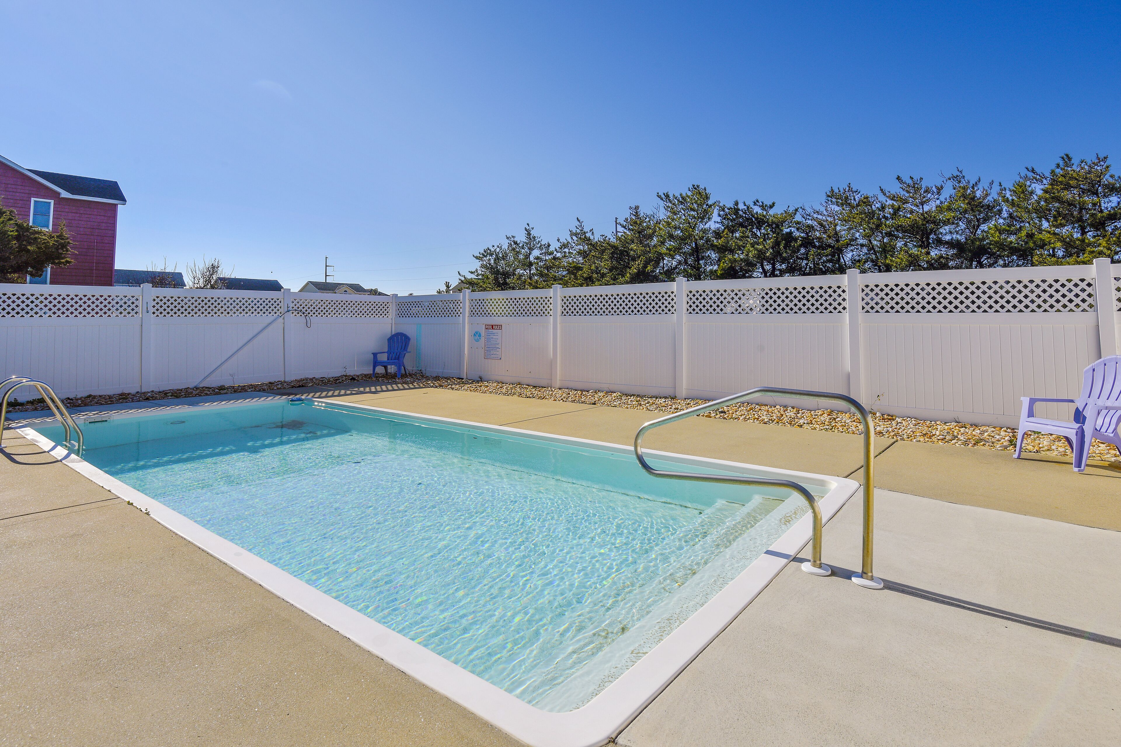 A rectangular swimming pool with a white deck and a metal ladder.
