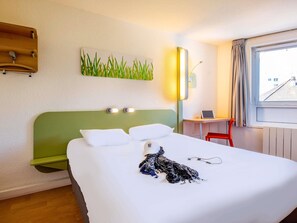 Une chambre d’hôtel avec un lit, un bureau, une chaise, une lampe et une fenêtre donnant sur un beau paysage.