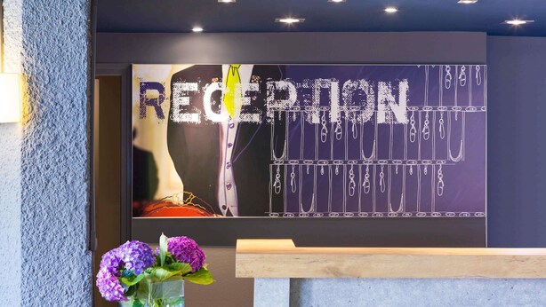 A reception desk with a chalkboard sign that reads "RECEPTION" and "FASHION". - ibis budget Limoges (Limoges)
