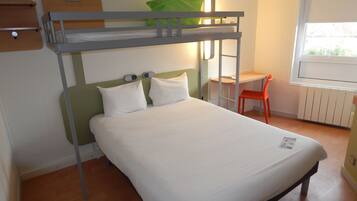 A bunk bed with a desk and chair, a window with a view, and a radiator.