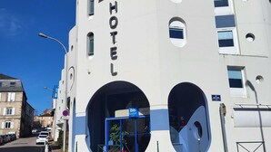 A hotel with a modern design, featuring a prominent 'ibis budget' sign, a large entrance with a blue archway, and a clear view of the street. - ibis budget Limoges (Limoges)