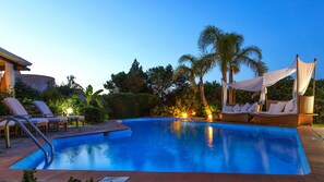 A swimming pool with lounge chairs and a canopy.