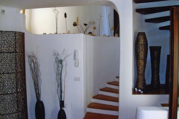 A staircase with wooden steps and a white wall with decorative plants and a textured wall hanging.