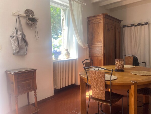A dining area with a wooden table and chairs, a cabinet, and a window with curtains. - House / Villa - Guérande (Guérande)