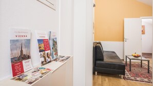 Una habitación con una cama, una mesita con fruta y un cartel con el mapa de la ciudad de Viena y museos.