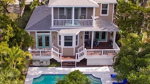 A two-story house with a balcony and a swimming pool. - 4BR Siesta Key lagoon home w/ heated pool (Sarasota)