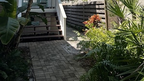 A house with a porch, a brick pathway, and various tropical plants. - 4BR Siesta Key lagoon home w/ heated pool (Sarasota)