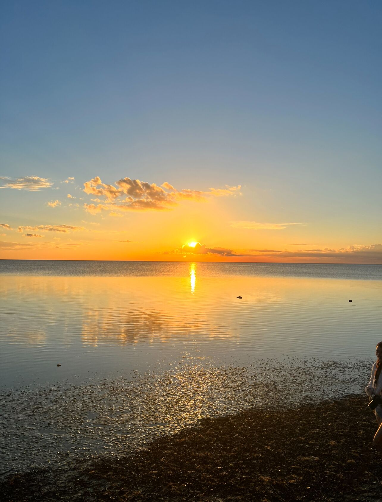 Mar tranquila al atardecer bajo un cielo despejado.