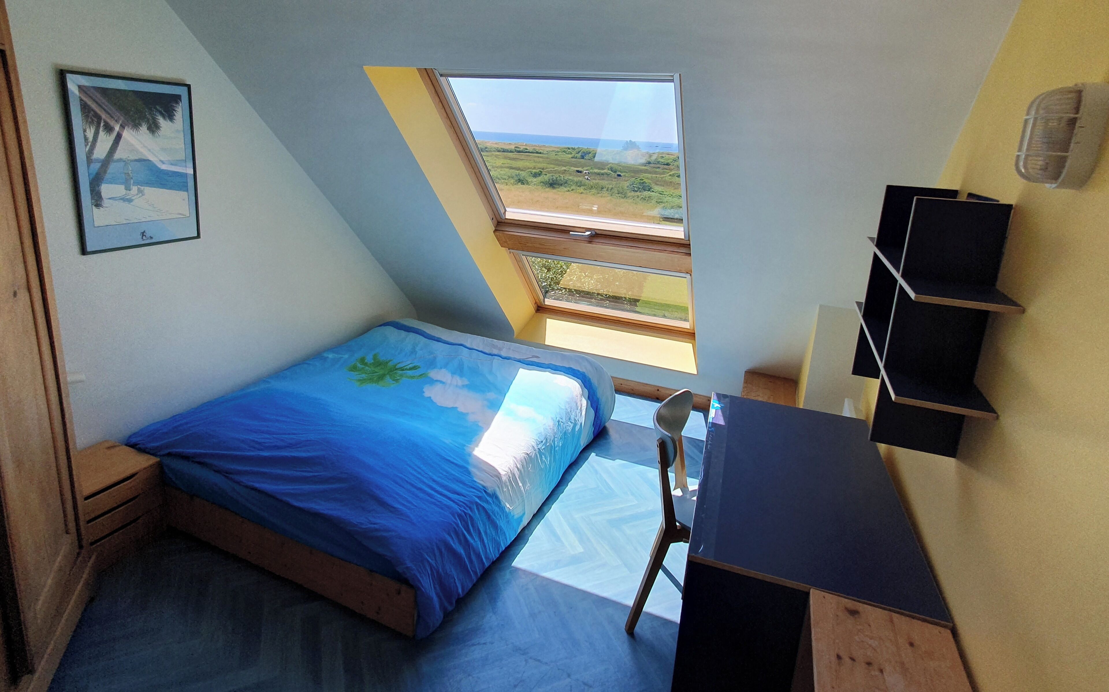 A bedroom with a bed, a desk, a chair, a window, and a shelf.