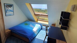 Una camera da letto con un letto, una scrivania, una sedia, una finestra e uno scaffale.