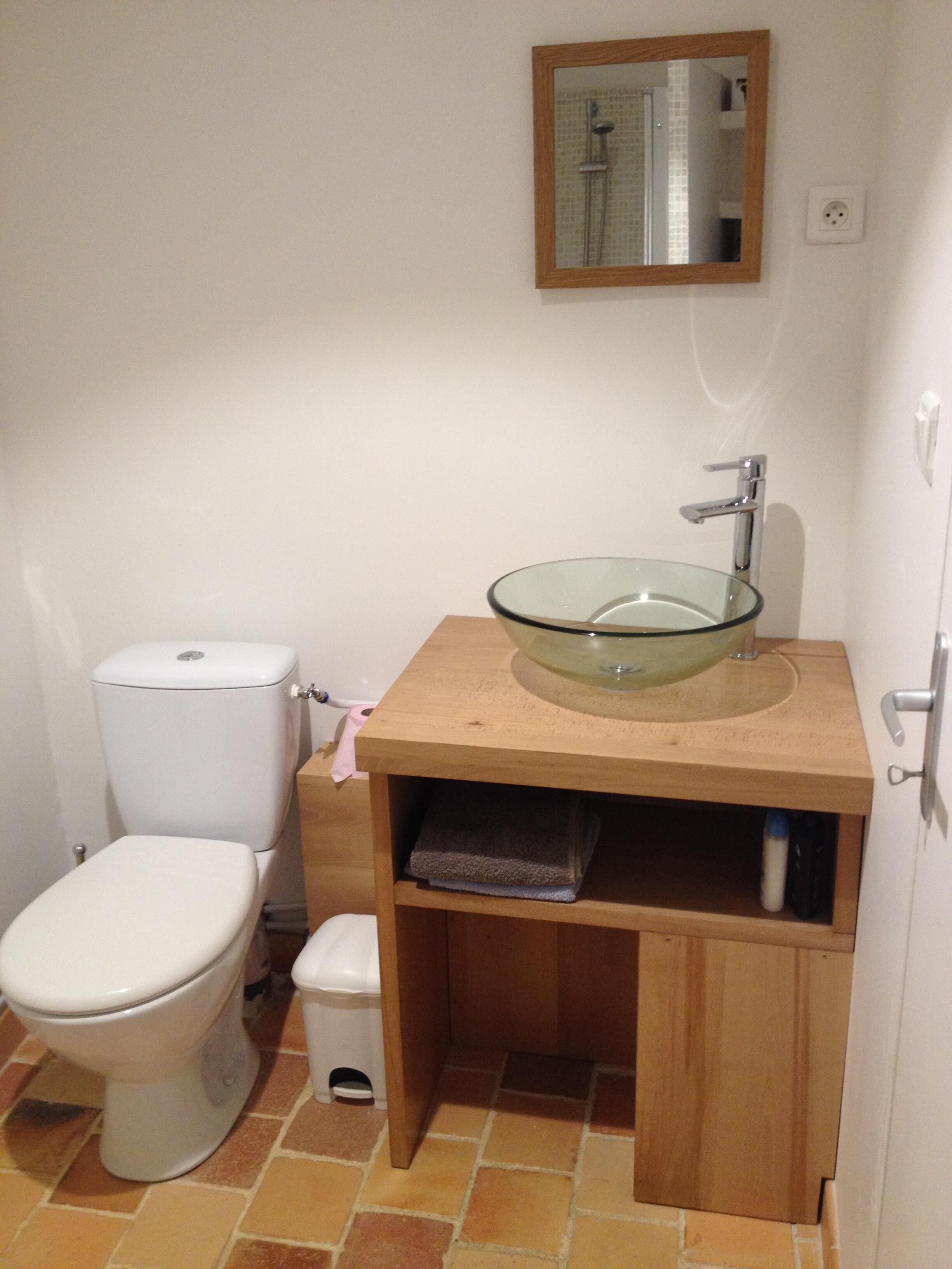 Un baño con inodoro, lavabo de vidrio y espejo.
