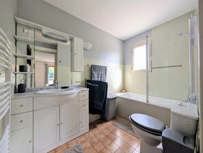 Un baño con tocador blanco, bañera, inodoro y ducha.
