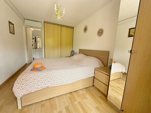 Un dormitorio con una cama de madera, una mesita de noche, un aparador, un espejo y una araña.