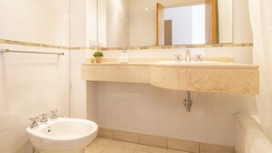 Ein modernes Badezimmer mit einem weißen Waschbecken, einem Bidet und einem Spiegel darüber.
