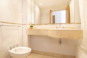 A modern bathroom with a white sink, a bidet, and a mirror above the sink.