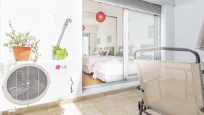 Ein Balkon mit einem Stuhl, einem Blumentopf und einer Klimaanlage.