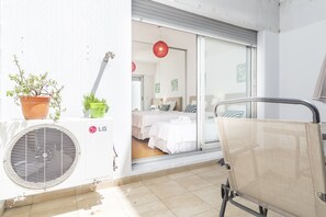 A balcony with a chair, a potted plant, and an air conditioning unit.