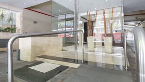 Ein moderner Innenbereich mit Glaswänden, einer Betonbank und einem Metallgeländer.
