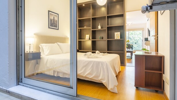 Ein modernes Schlafzimmer mit Bett, Nachttischen, Schreibtisch und Regalelement.