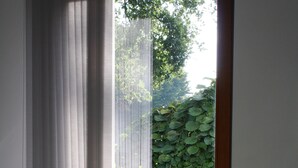 Un coin repas comprenant une table, des chaises, un vase de fleurs et une vue sur un jardin, visible à travers une porte vitrée.
