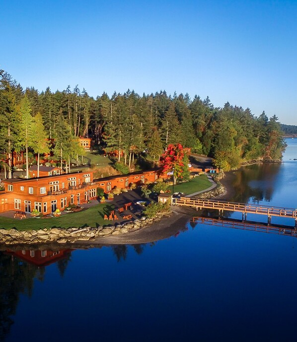 A waterfront property with a brick building, a dock, and a forested area. - Snug Harbor Resort (Friday Harbor)