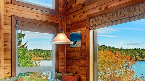A wooden cabin interior with a dining table, chairs, and a bench. - Snug Harbor Resort (Friday Harbor)